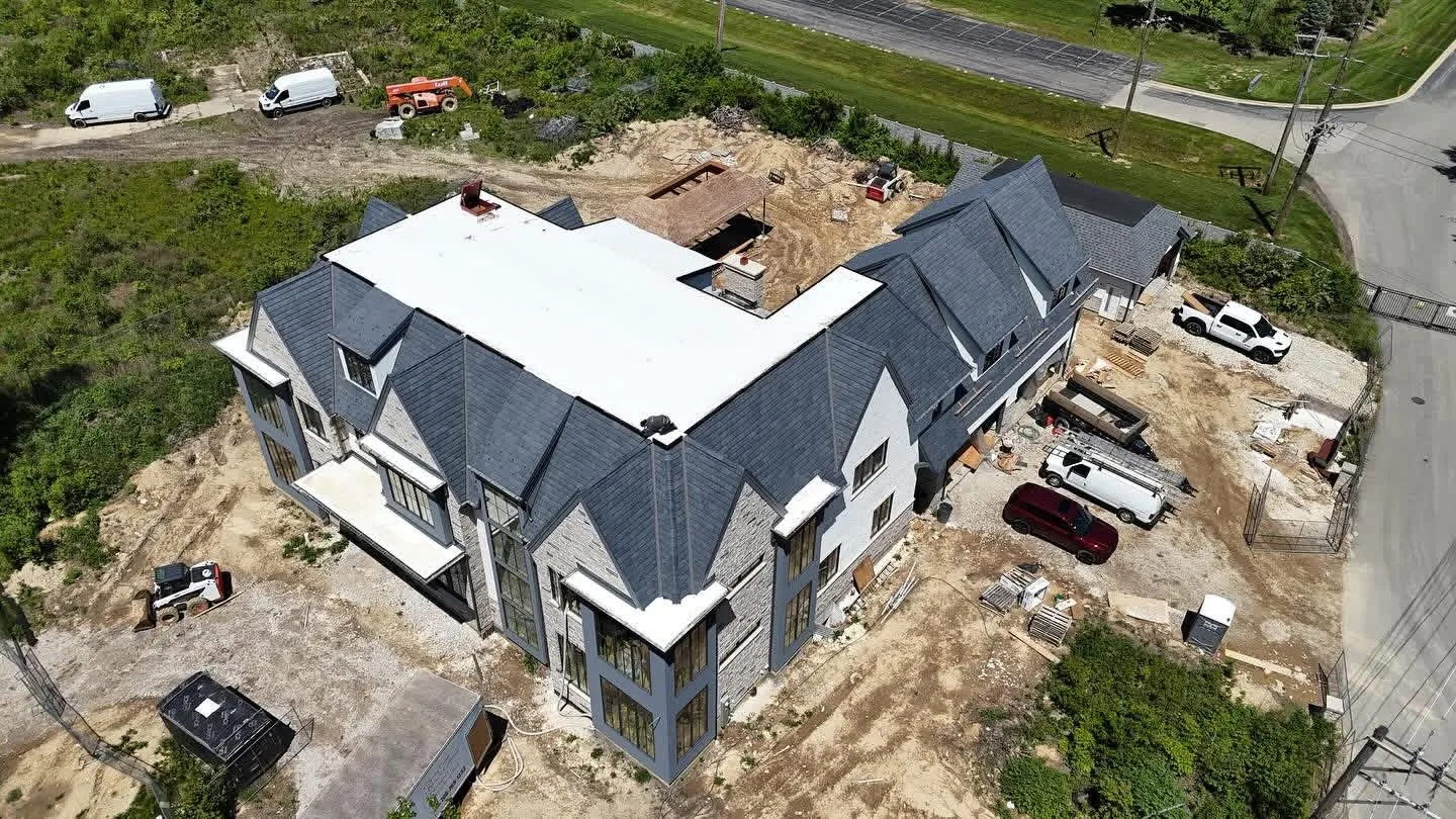 Slate look roof and white flat membrane section on a home under construction