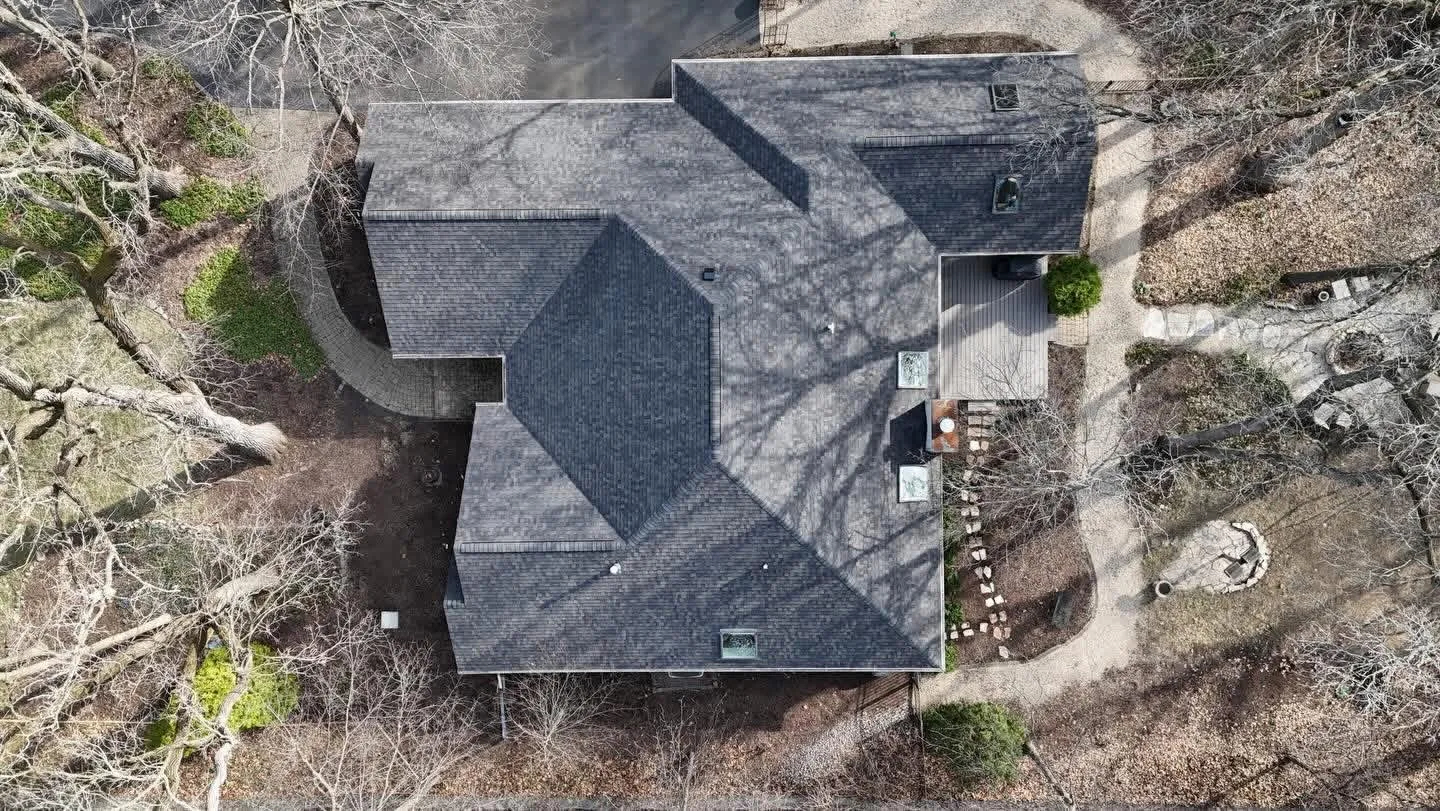 Finished charcoal asphalt shingle roof on a home backing onto woods