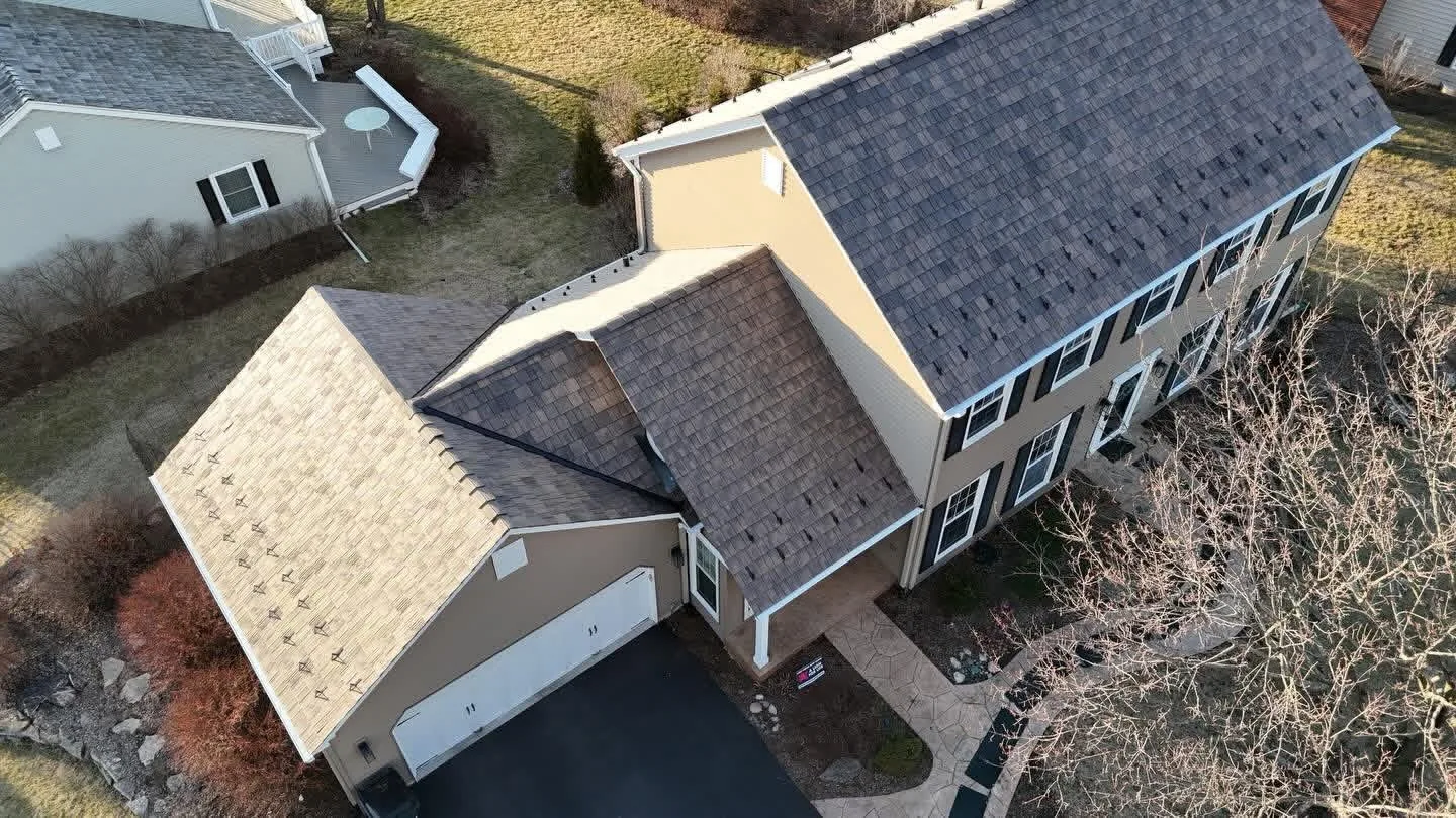 Roof replacement underway with synthetic underlayment and roof jacks on the garage slope